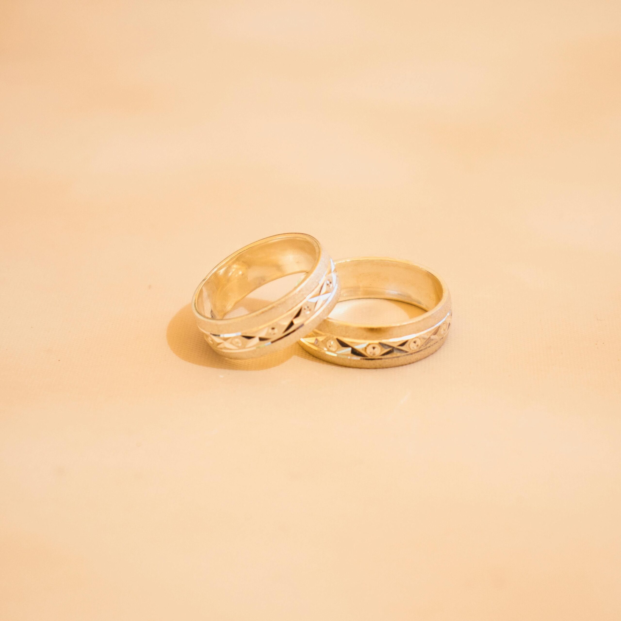 Close-up of two elegant gold wedding rings on a neutral background, symbolizing love and commitment.